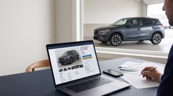 Buyer cross-checking an online vehicle listing, paperwork, and the matching car before purchase