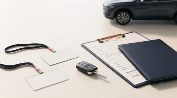 Car key, auction credential, dealer folder, and vehicle paperwork arranged for a U.S. car buying comparison