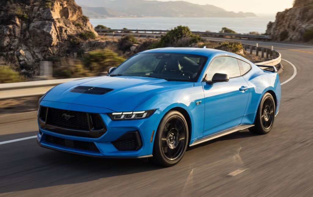 Grabber Blue Metallic 2026 Ford Mustang sports car driving on a coastal highway featured for global export / import Ford Mustang from USA services.